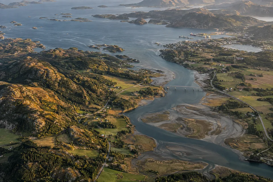 Aerial view of a coastal estuary with roads, fields and a bridge